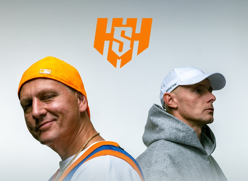 Dwóch mężczyzn na białym tle z pomarańczowym logo HSH; kontrast uśmiechu i powagi, styl streetwear.