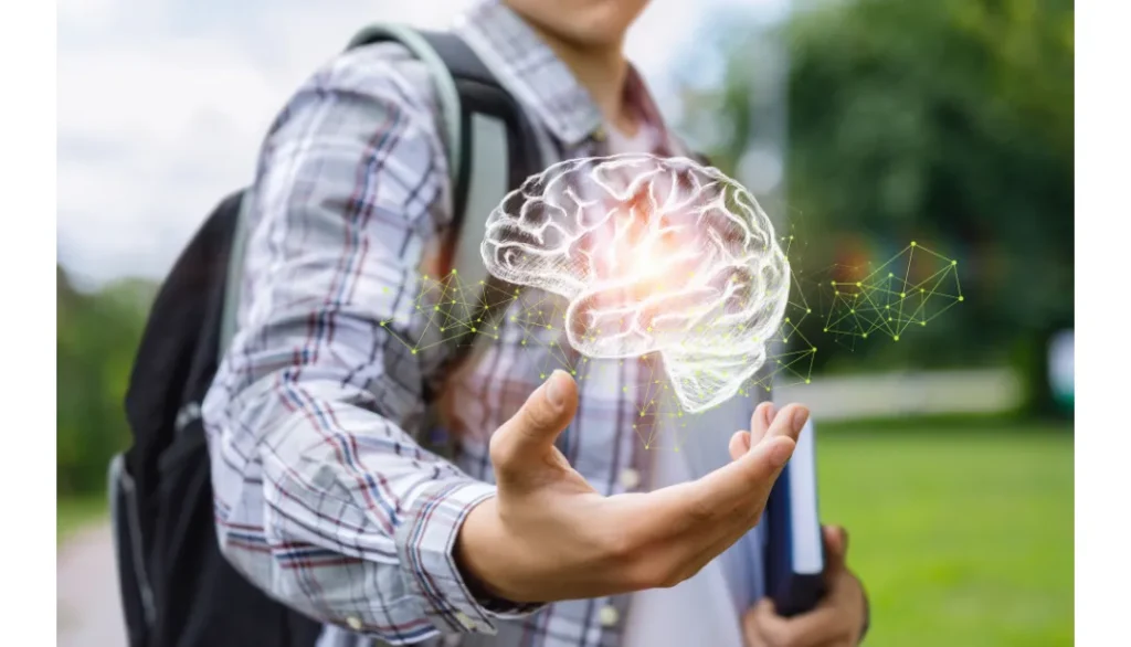 Osoba w parku trzyma dłoń z hologramem mózgu; w drugiej ręce ma notes i plecak